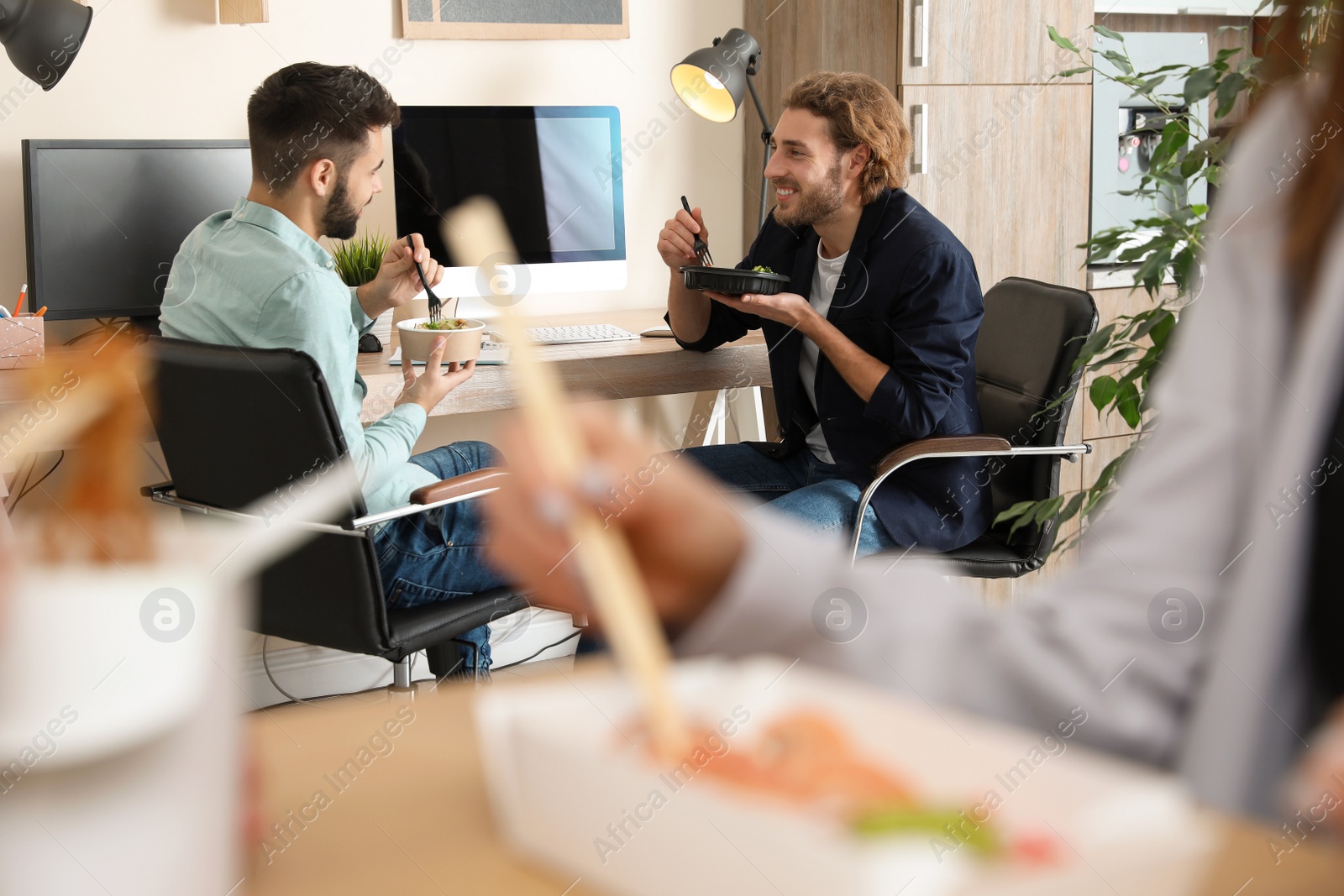 Photo of Office employees having lunch at workplace. Food delivery