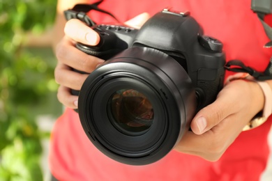 Female photographer with professional camera on blurred background, closeup