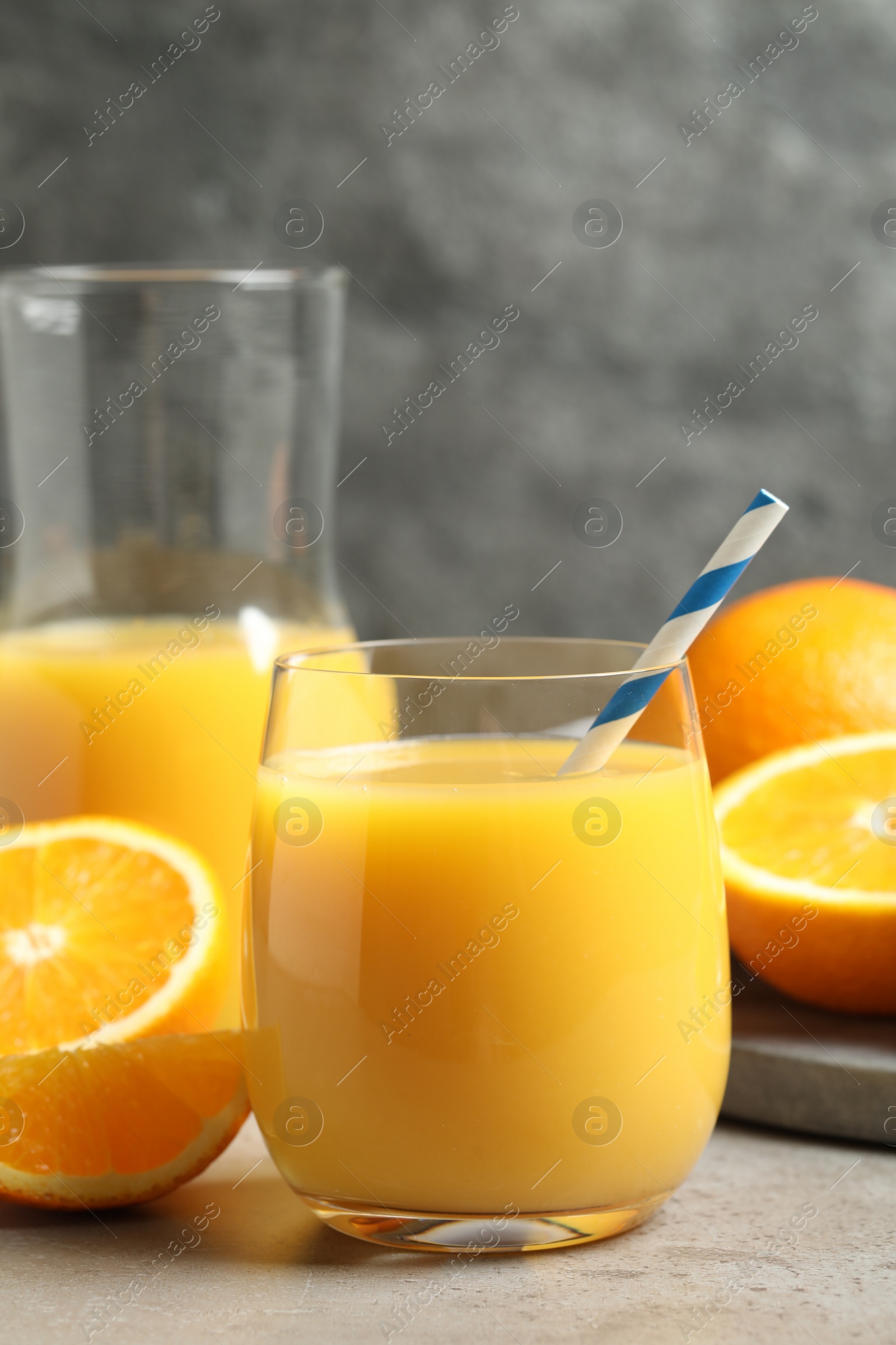 Photo of Glass of orange juice and fresh fruits on grey table