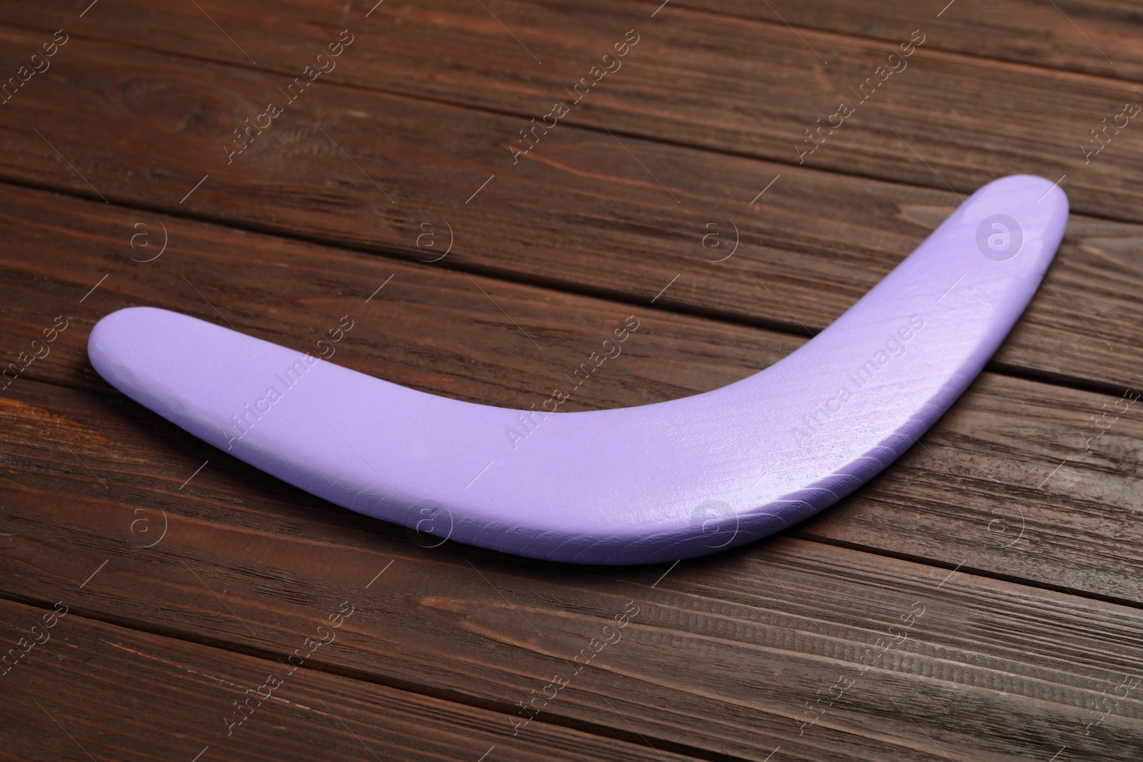 Photo of Purple boomerang on wooden background. Outdoors activity