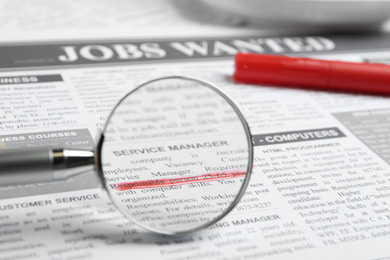 Photo of Looking through magnifying glass at newspaper, closeup. Job search concept