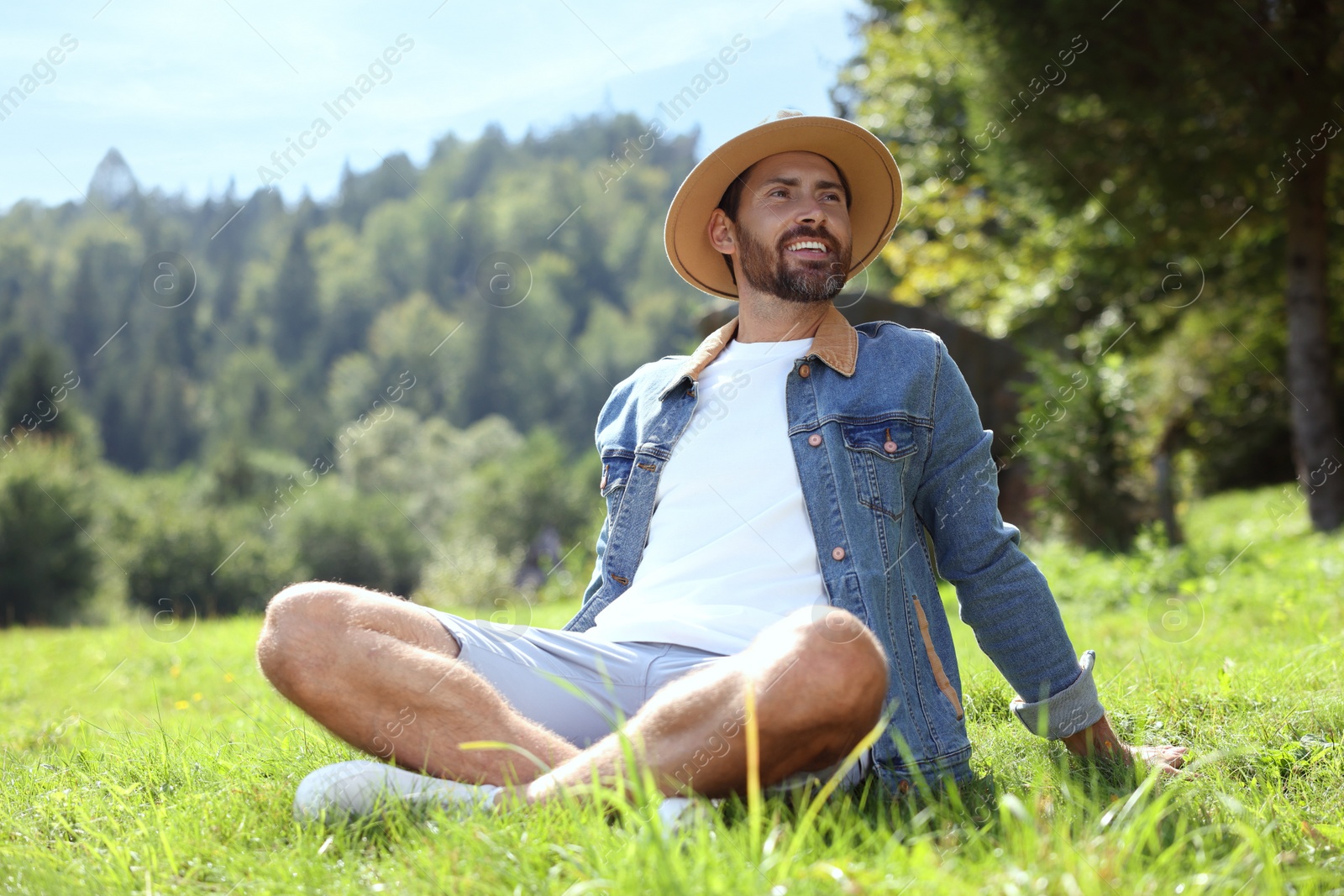 Photo of Feeling freedom. Smiling man enjoying nature on green grass outdoors