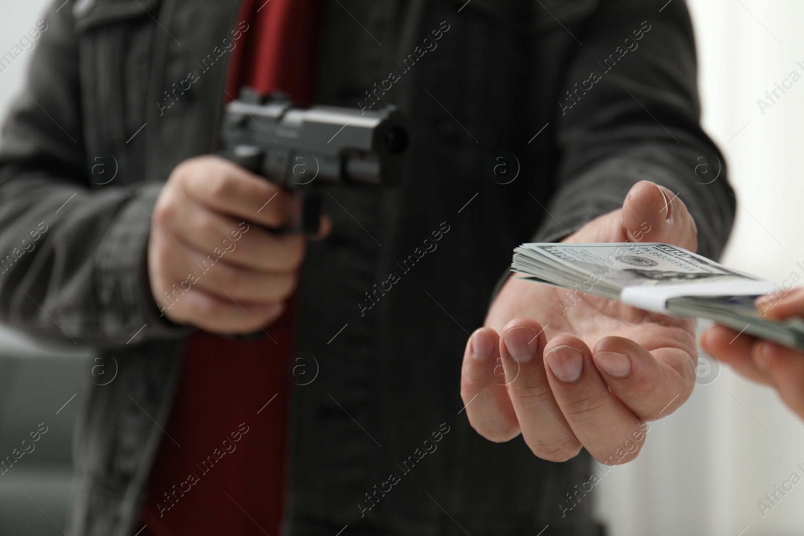 Photo of Woman giving money to criminal with gun indoors, closeup. Armed robbery