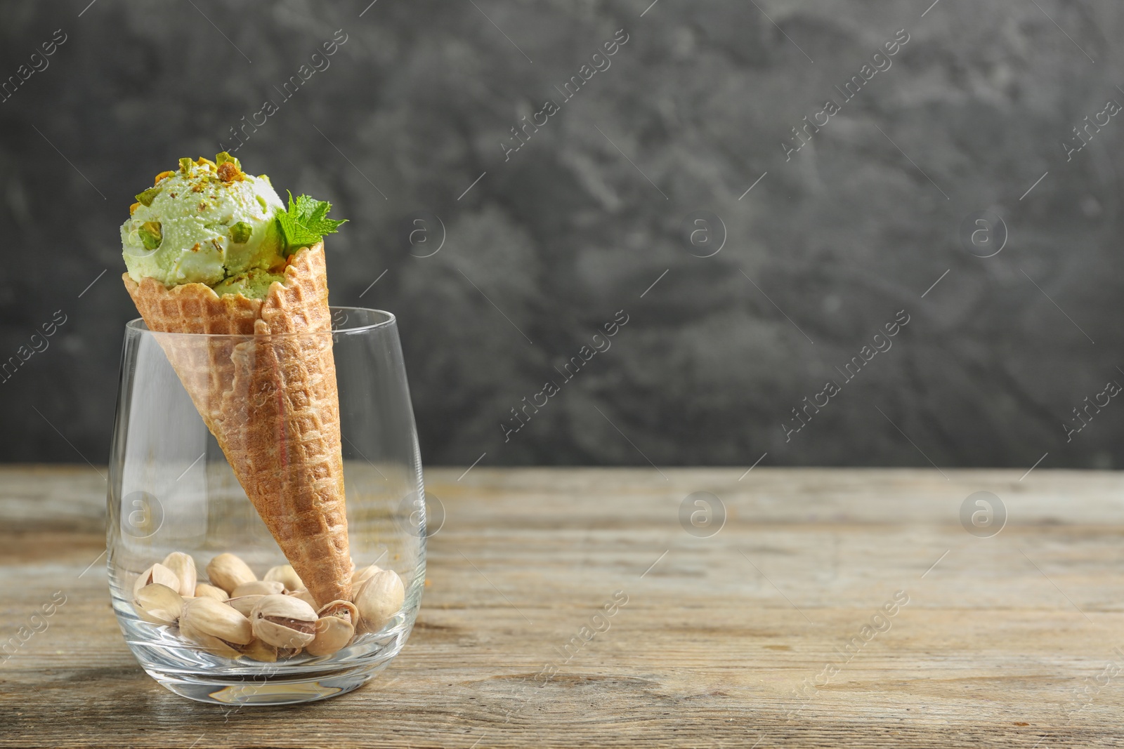 Photo of Delicious green ice cream served on wooden table. Space for text