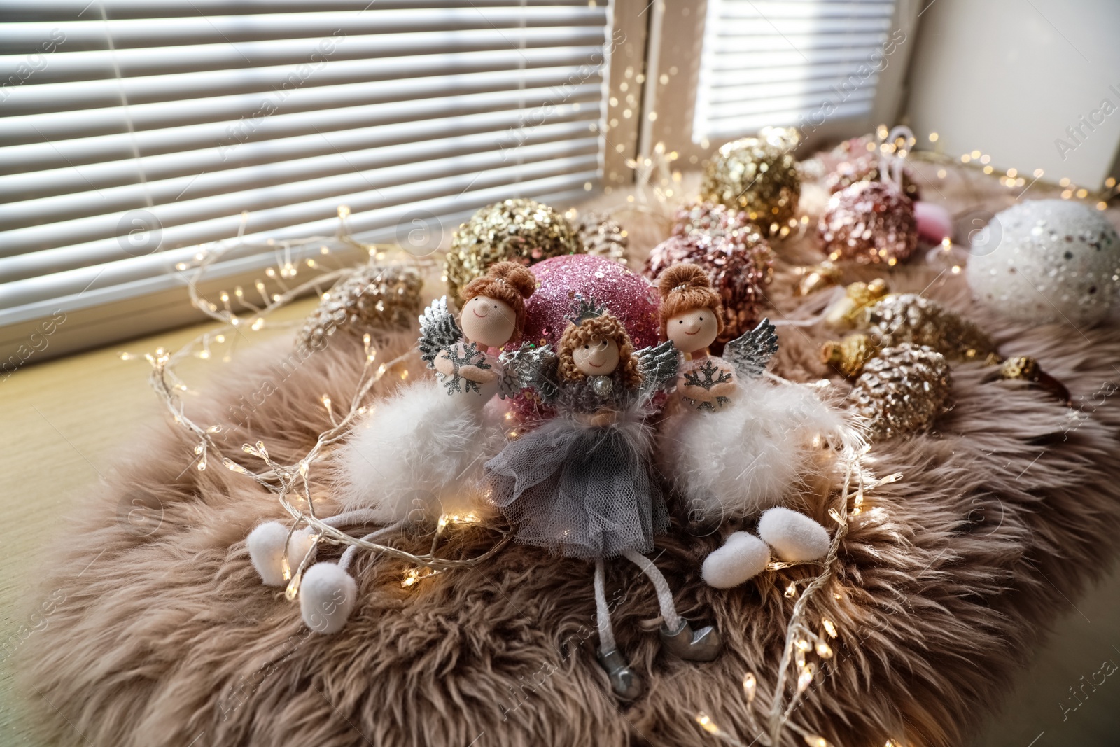 Photo of Beautiful angel dolls and shiny bauble on window sill indoors