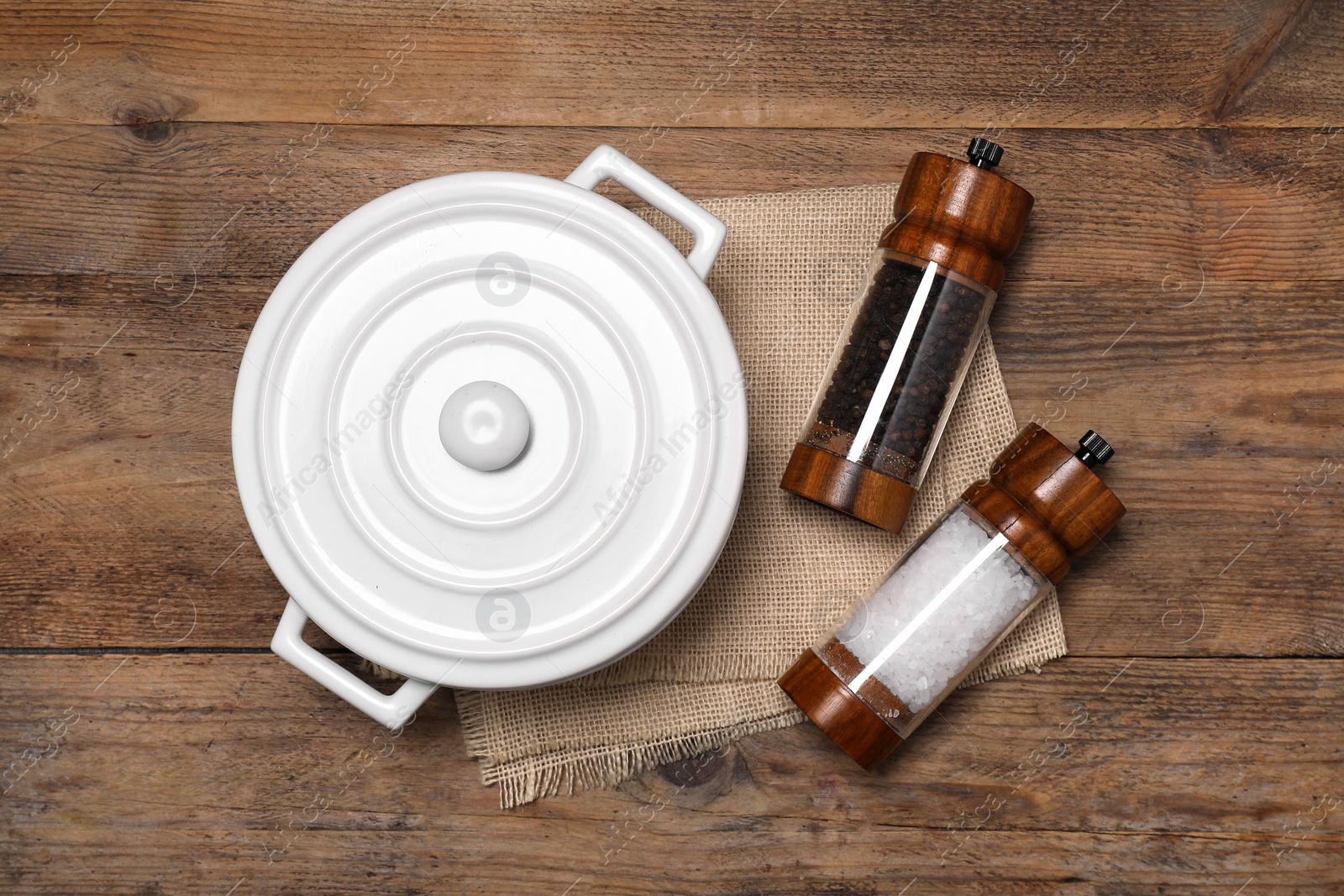 Photo of White pot with salt and pepper shakers on wooden table, flat lay