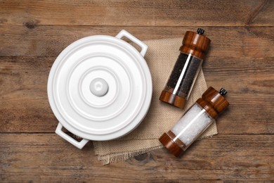 Photo of White pot with salt and pepper shakers on wooden table, flat lay