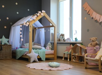 Stylish child room interior with house bed and different toys