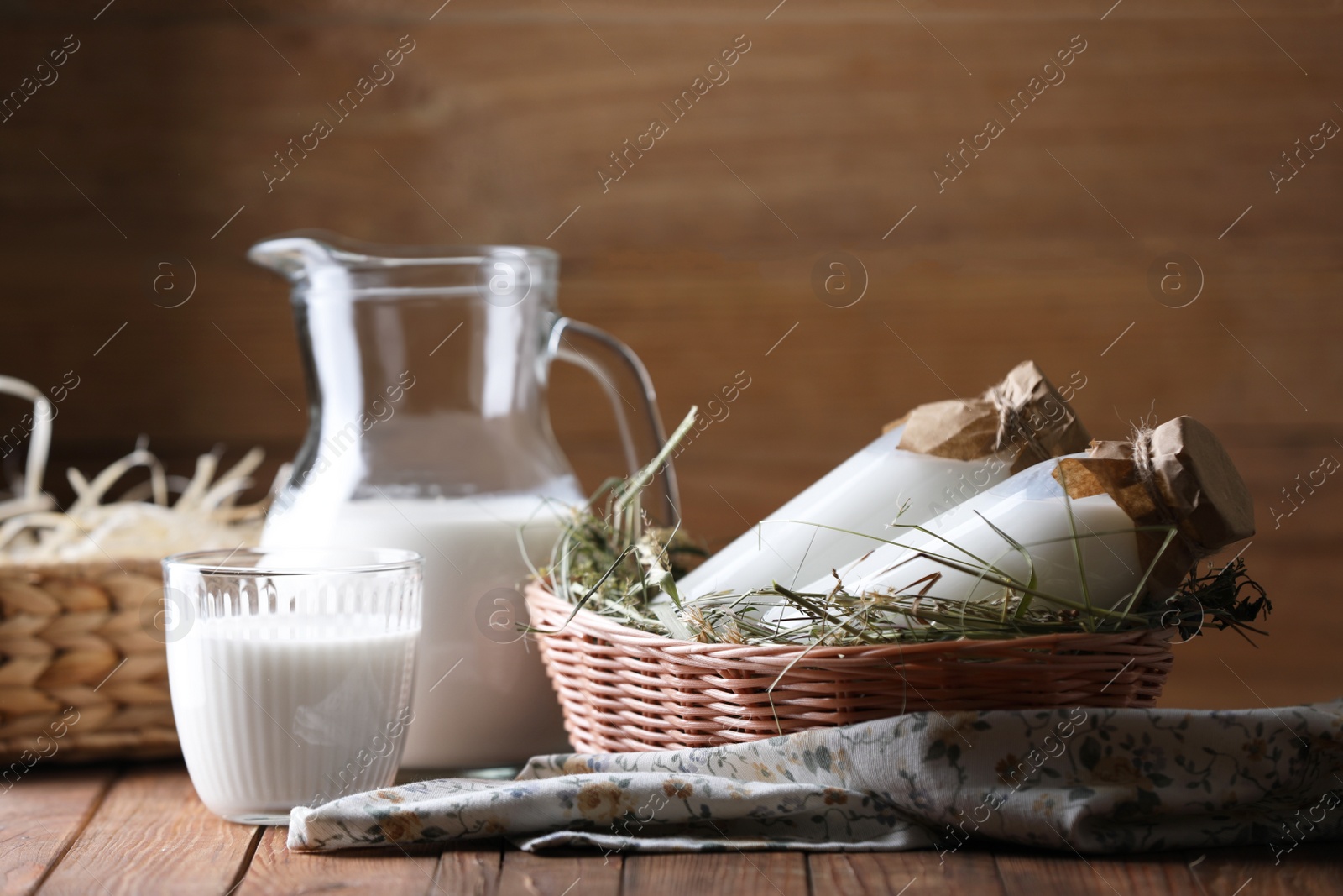 Photo of Tasty fresh milk in jug, bottles and glass on wooden table