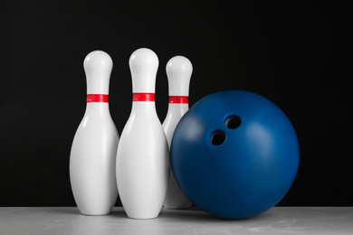 Photo of Blue bowling ball and pins on light grey marble table