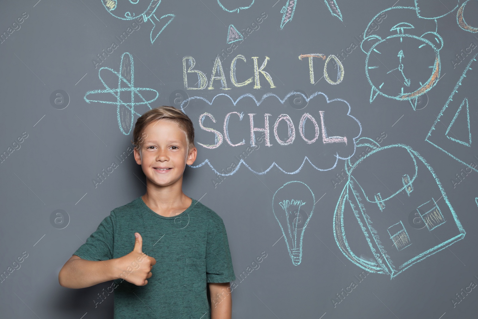Photo of Little child near drawings and text BACK TO SCHOOL on grey background