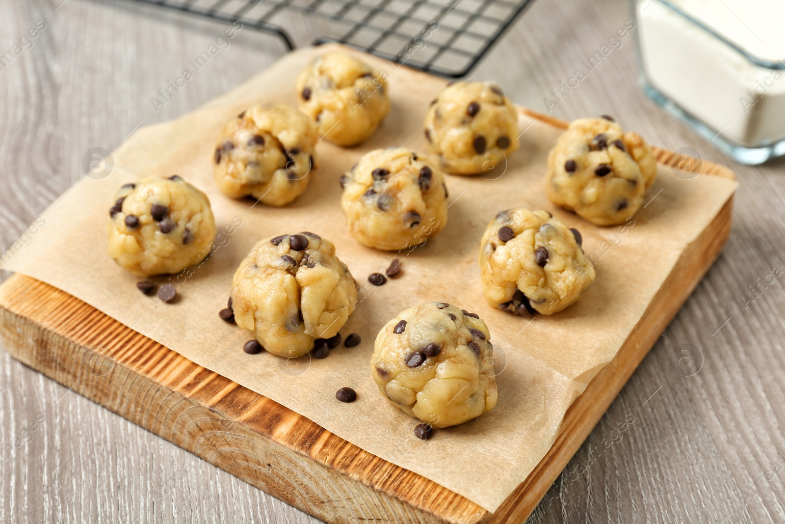 Photo of Raw cookie dough with chocolate chips on wooden board