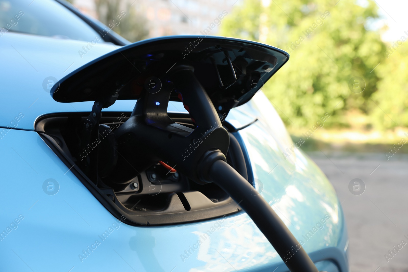 Photo of Charging modern electric car from station outdoors, closeup