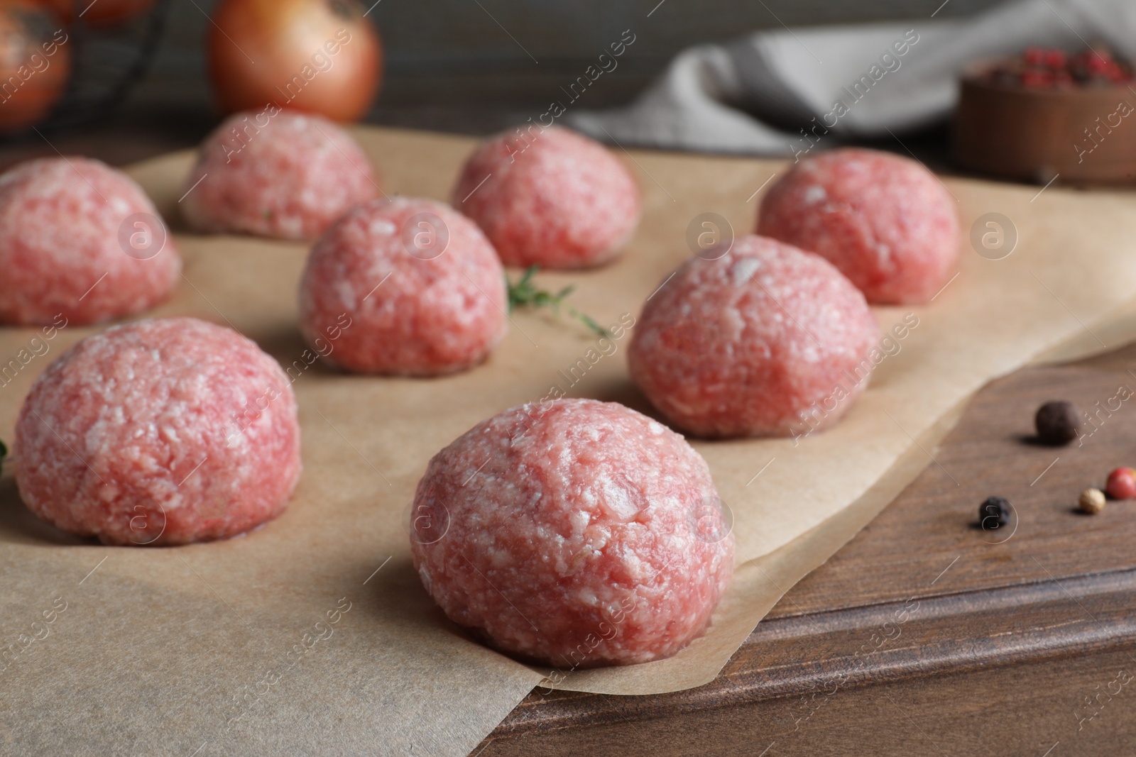Photo of Many fresh raw meatballs on wooden board, closeup