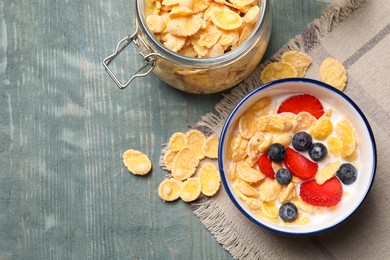 Delicious crispy cornflakes with milk and fresh berries on light blue wooden table, flat lay. Space for text