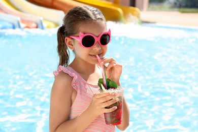 Girl with delicious refreshing drink near swimming pool