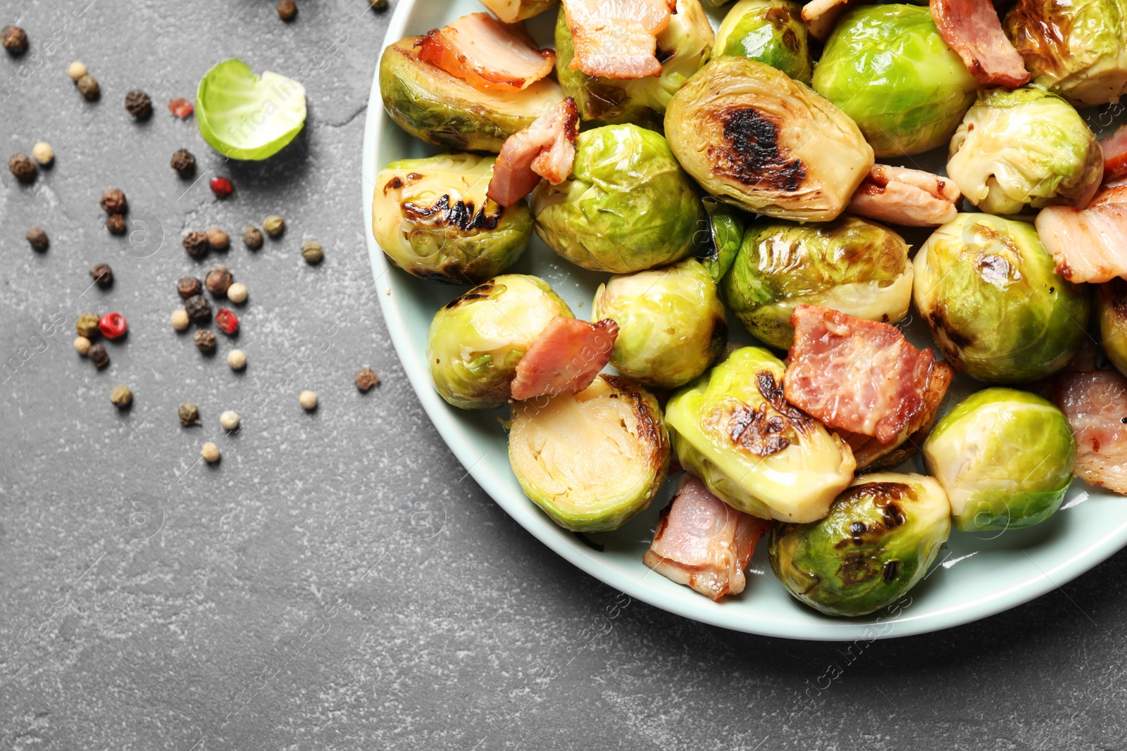 Image of Delicious fried Brussels sprouts with bacon on grey table, flat lay