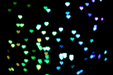 Blurred view of heart shaped lights on black background. Bokeh effect