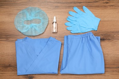 Photo of Flat lay composition with medical uniform and rubber gloves on wooden table