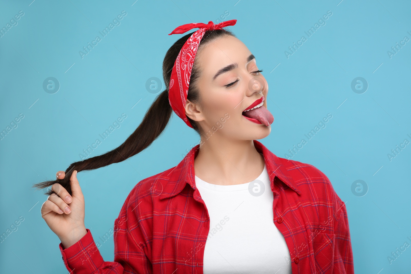 Photo of Happy woman showing her tongue on light blue background