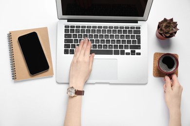 Photo of Woman using laptop at white table, top view