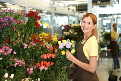 Photo of Female florist holding beautiful bouquet in flower shop