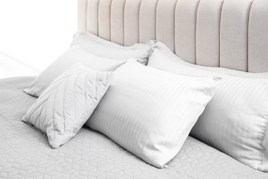 Photo of Many soft pillows on large comfortable bed indoors