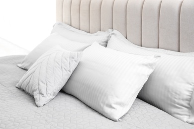 Many soft pillows on large comfortable bed indoors