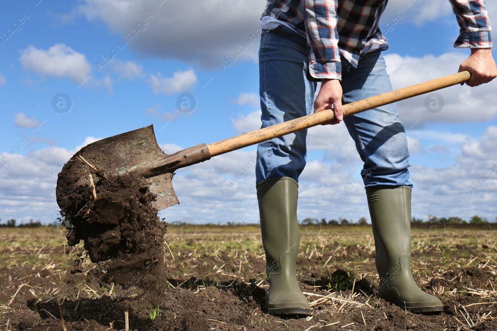 Photo of Man digging soil with shovel in field, closeup