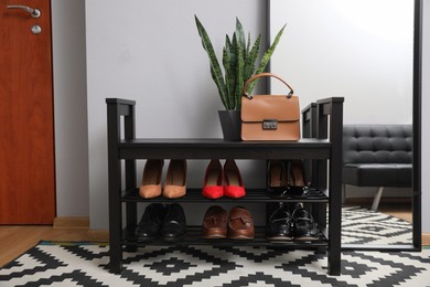 Photo of Shelving unit with stylish shoes and large mirror near grey wall in hallway