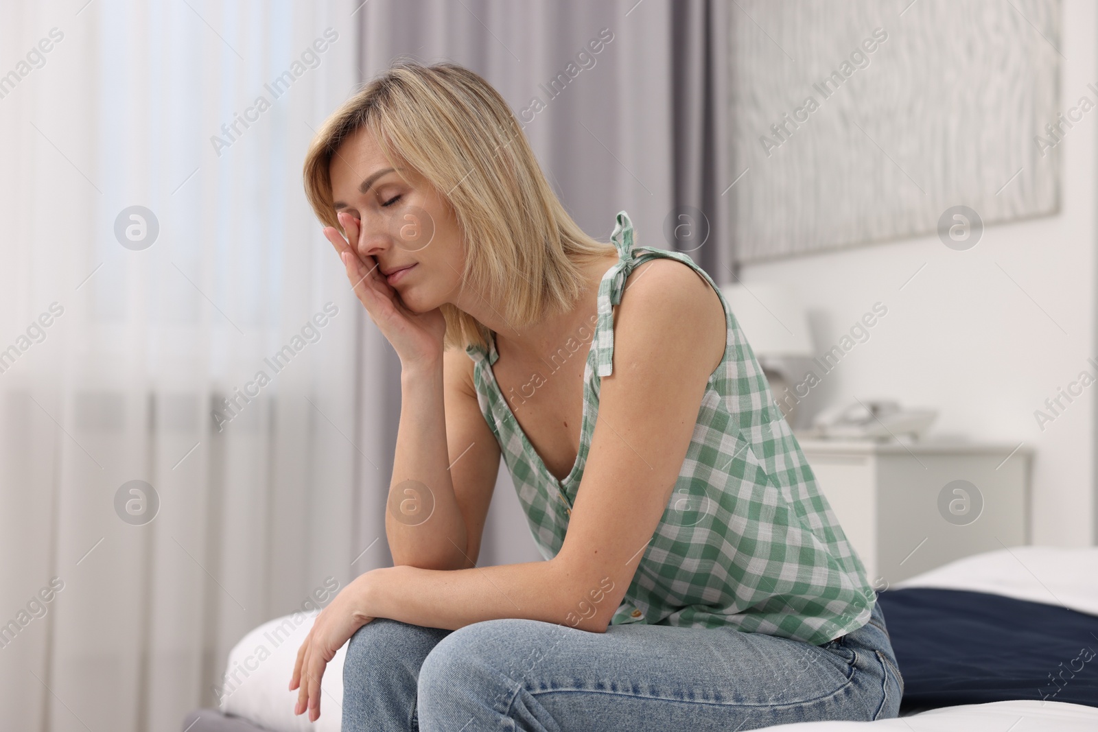 Photo of Overwhelmed woman sitting on bed at home