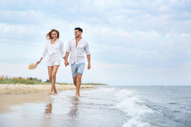 Photo of Happy couple having romantic walk on beach. Space for text