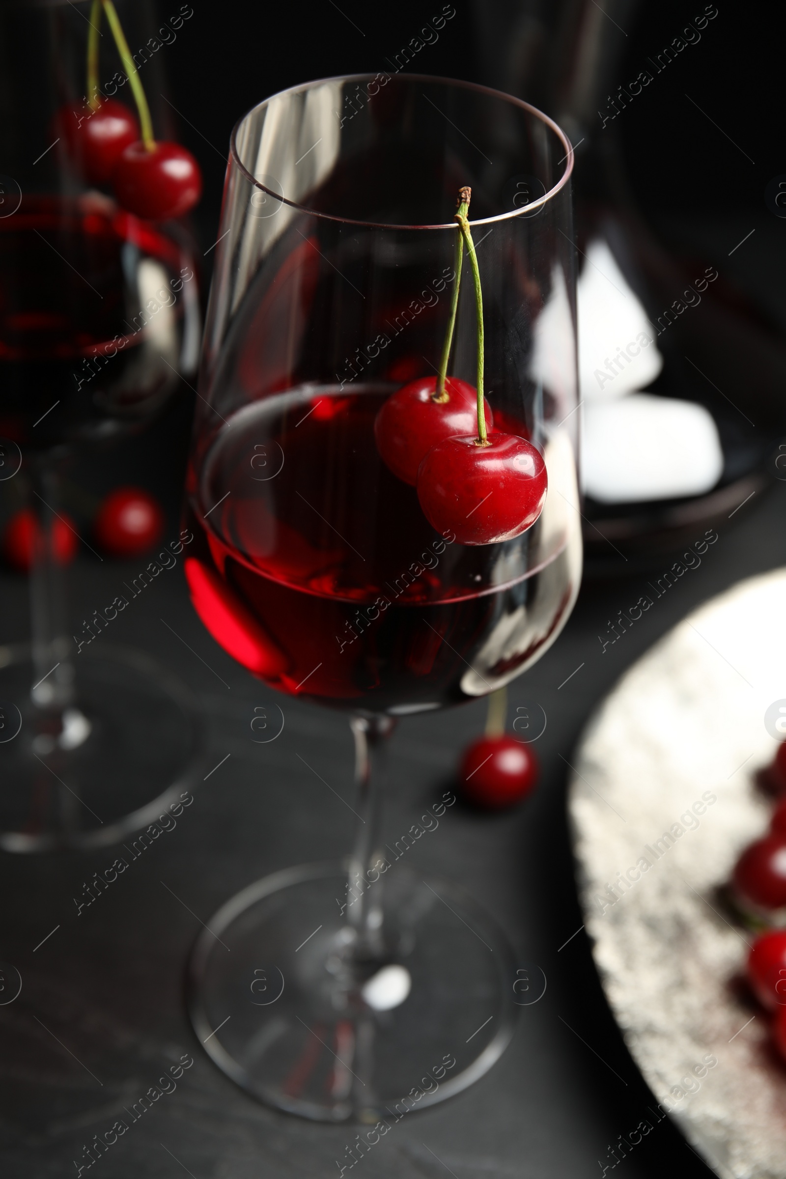 Photo of Delicious cherry wine with ripe juicy berries on grey table