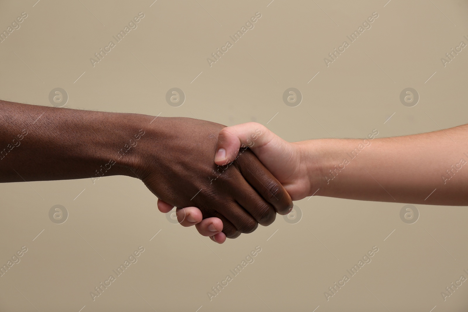 Photo of Men shaking hands on beige background, closeup