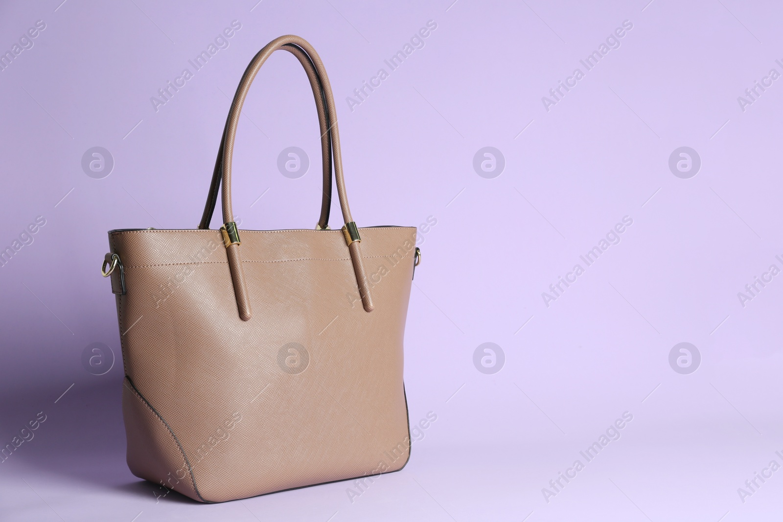 Photo of Stylish woman's bag on lilac background. Space for text