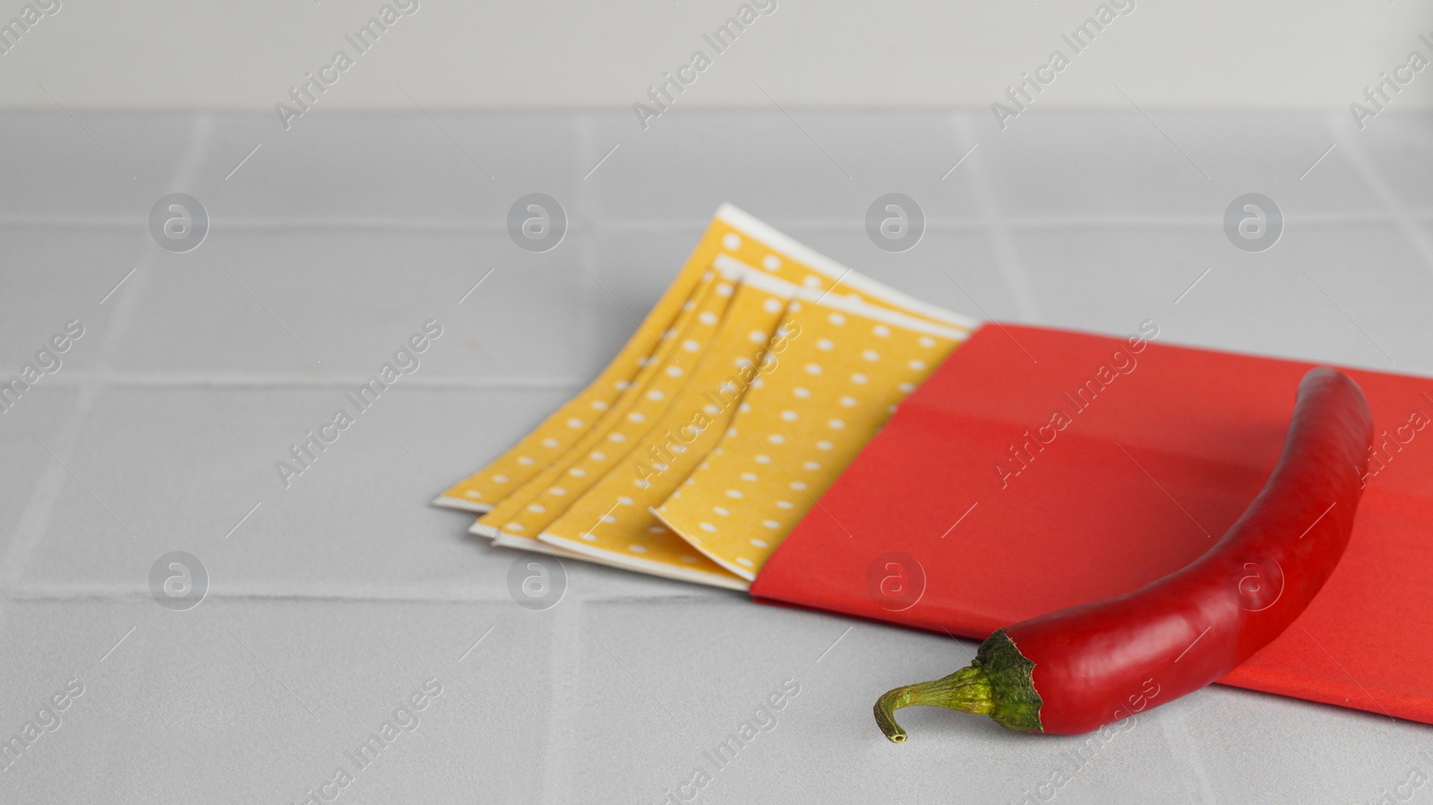 Photo of Pepper plasters and chili on white tiled table, closeup. Space for text