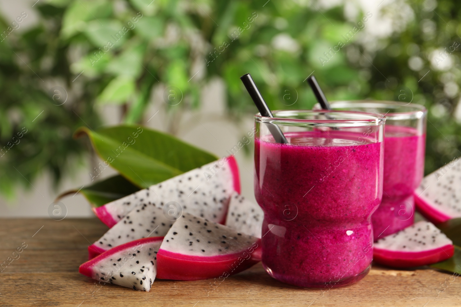 Photo of Delicious pitahaya smoothie and fresh fruits on wooden table, space for text