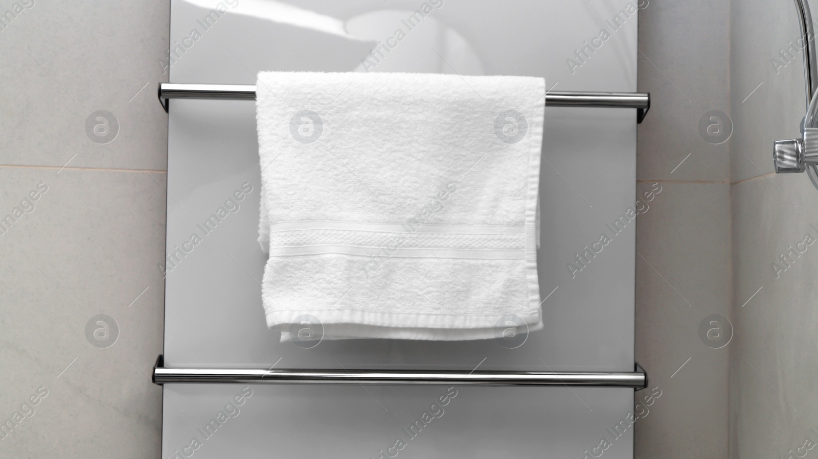 Photo of Clean towel on heated rail in bathroom