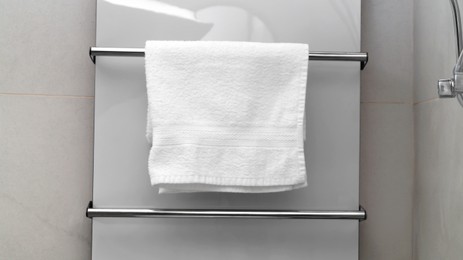 Photo of Clean towel on heated rail in bathroom