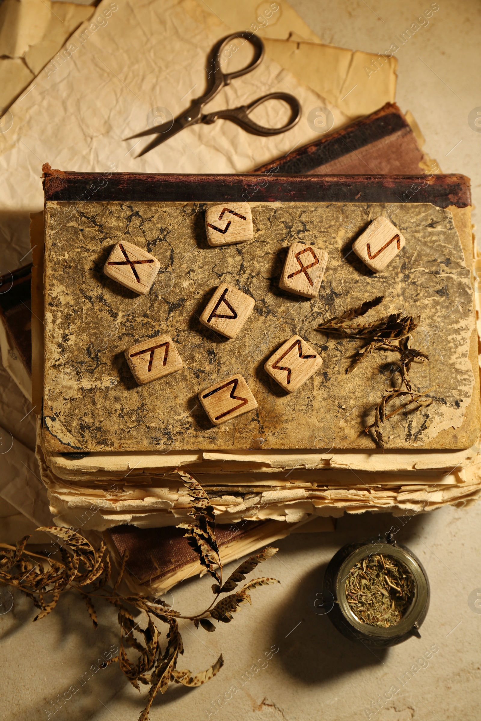 Photo of Wooden runes, dried plants and old books on beige table, flat lay