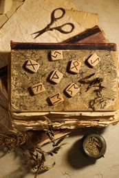 Photo of Wooden runes, dried plants and old books on beige table, flat lay