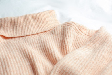 Stylish knitted sweater on white fabric, closeup