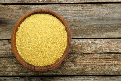 Photo of Bowl of raw couscous on wooden table, top view. Space for text