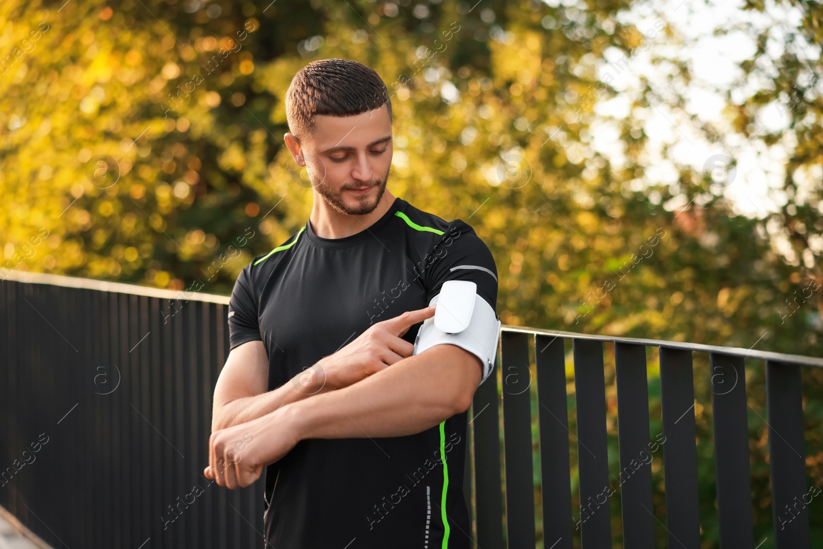 Photo of Attractive serious man checking blood pressure with modern monitor outdoors. Space for text