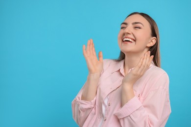 Beautiful woman laughing on light blue background. Space for text