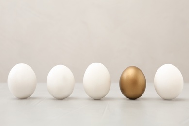 Golden egg among others on light background