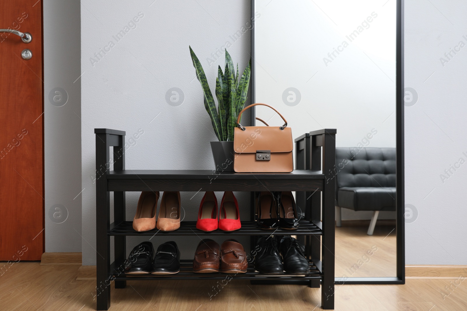 Photo of Shelving unit with stylish shoes and large mirror near grey wall in hallway