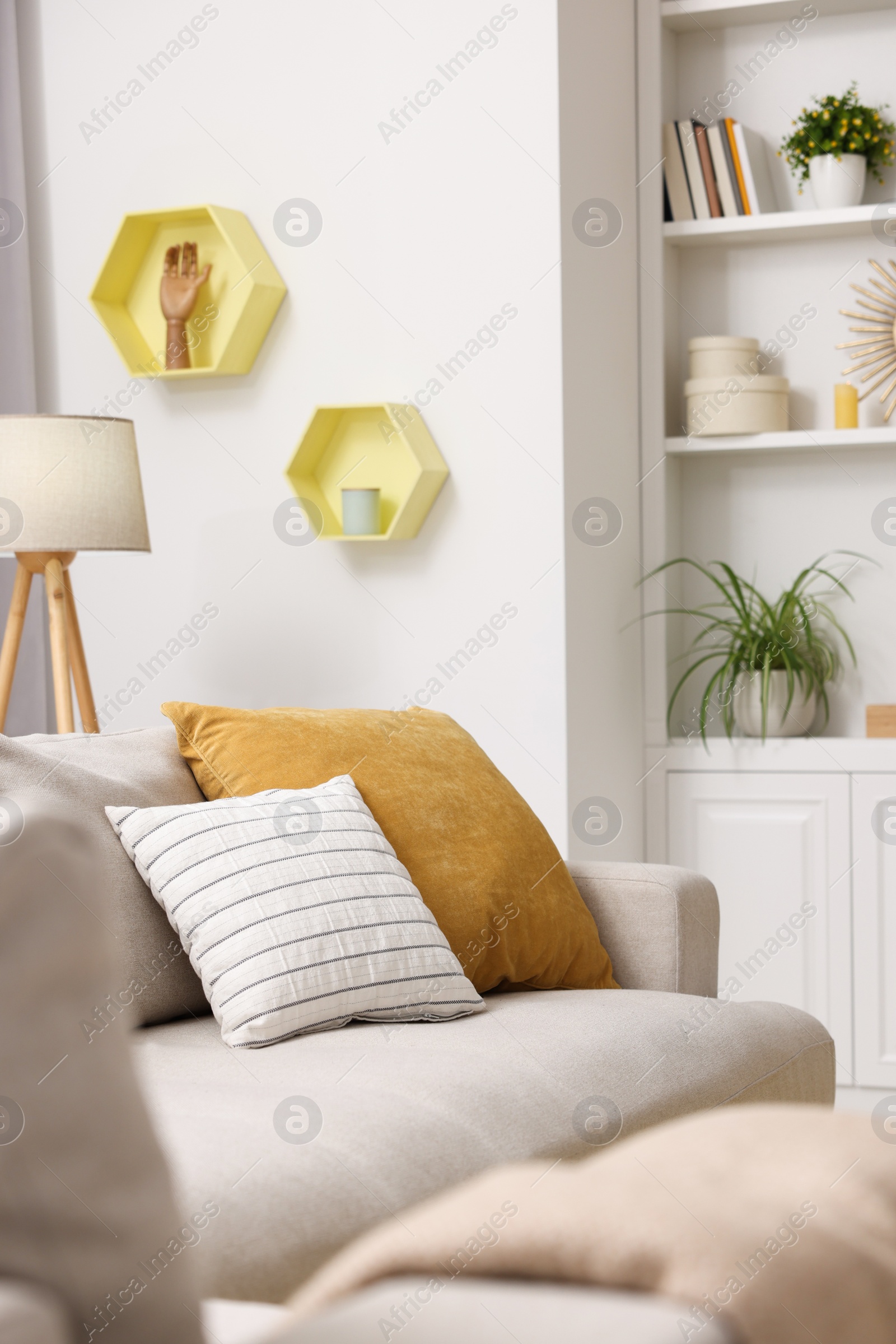 Photo of Spring atmosphere. Soft sofa, lamp and shelves with stylish accessories in room