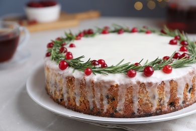 Traditional Christmas cake decorated with rosemary and cranberries on table, closeup