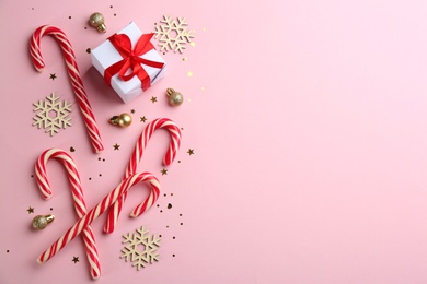Photo of Flat lay composition with candy canes and Christmas decor on pink background. Space for text